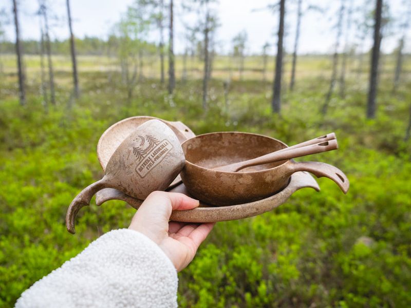 Mano con una kuksa y un bowl Kupilka en un bosque de Carelia, Finlandia